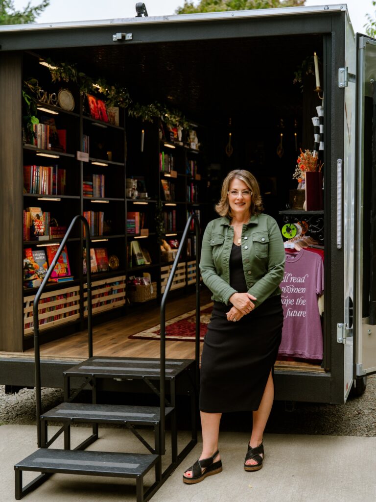Suzie Vasquez stands at the entrance to TBR on Tour, her mobile bookstore on wheels.