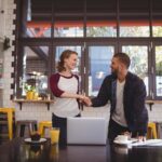 Business handshake at cafe table with laptop