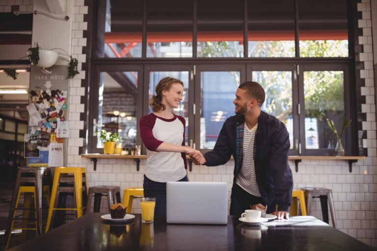 Business handshake at cafe table with laptop
