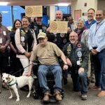 Washington Veterans Home residents, staff and community partners gather with a foster dog at the Port Orchard facility. The resident-run Foster Dog Program, a partnership with Kitsap Humane Society, provides temporary homes and care for senior shelter dogs while helping them find permanent homes. The program recently received a 2026 Abraham Lincoln Pillars of Excellence Award.